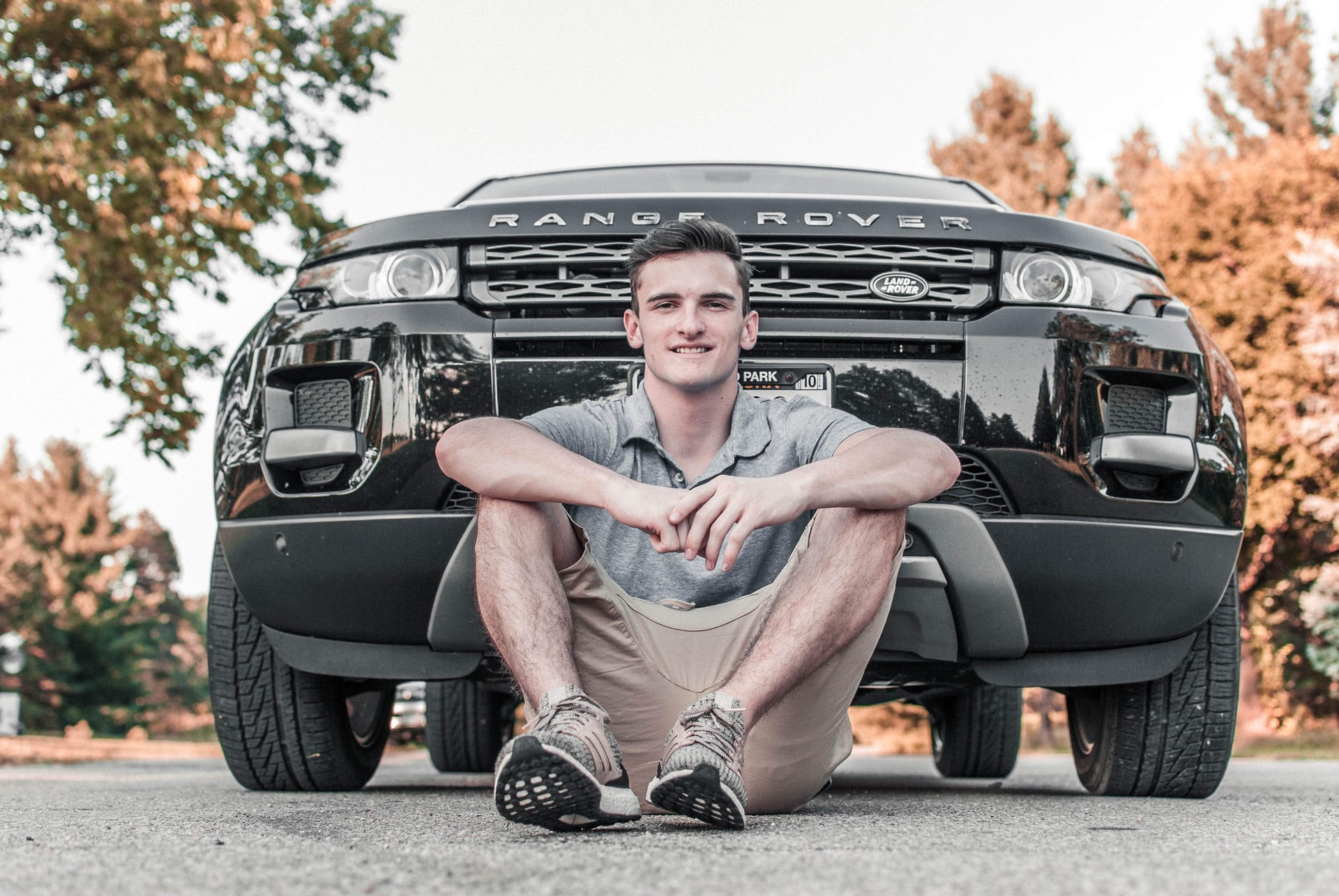 young male sitting in front of newly purchased car